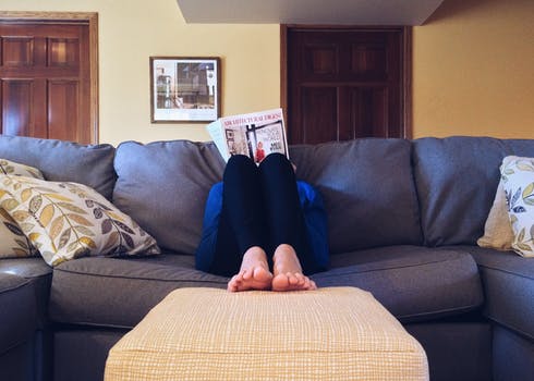 jeune personne lisant un magazine sur un canapé
